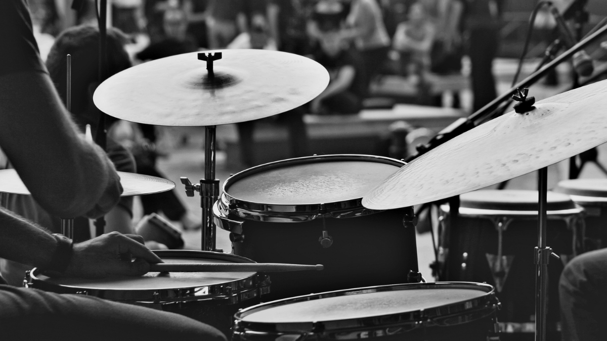 Black and white photo of a drum set and the arm of a drummer.